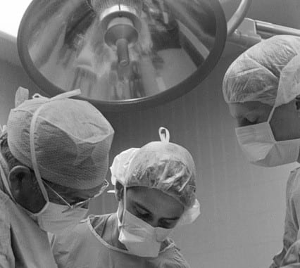 Black and white image of surgeons around an operating table.